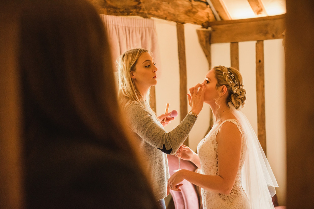 Makeup artist applying bridal makeup, blusher and final touch ups to the bride on her wedding morning